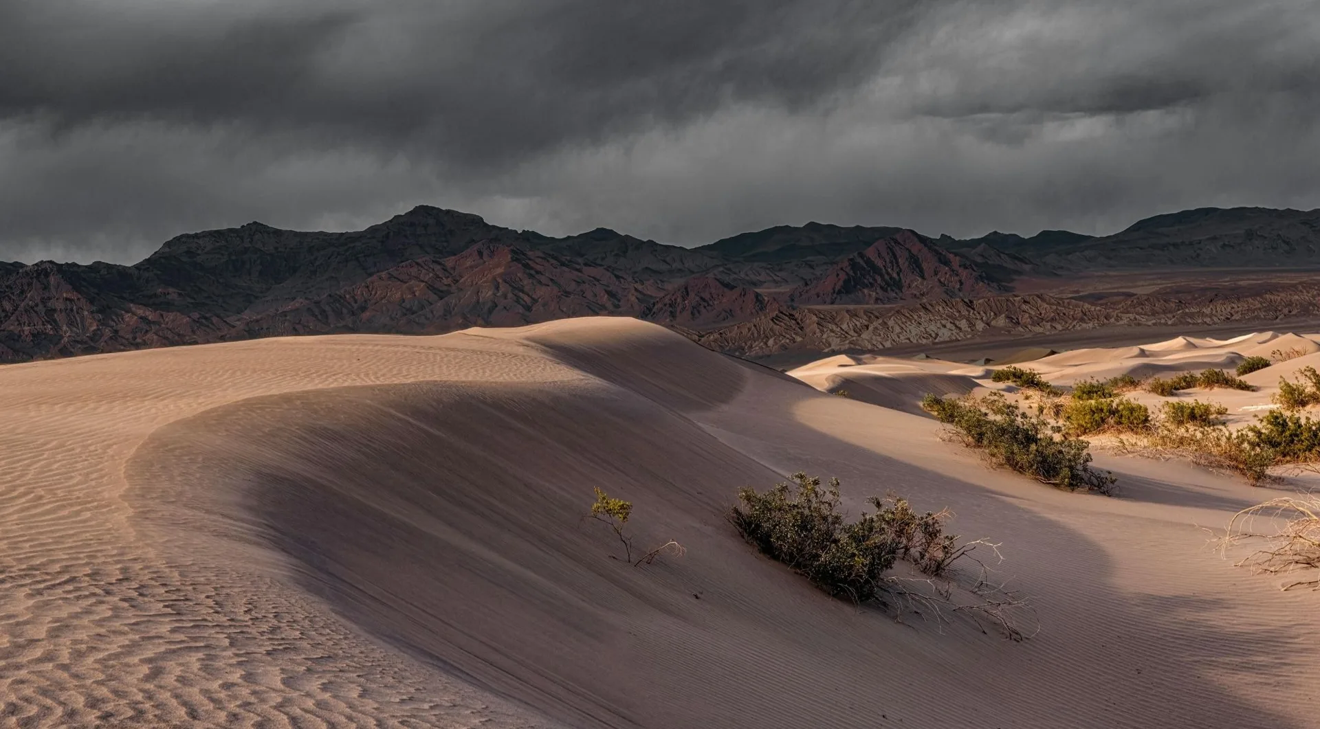 Wind-shaped sand dunes under clouds