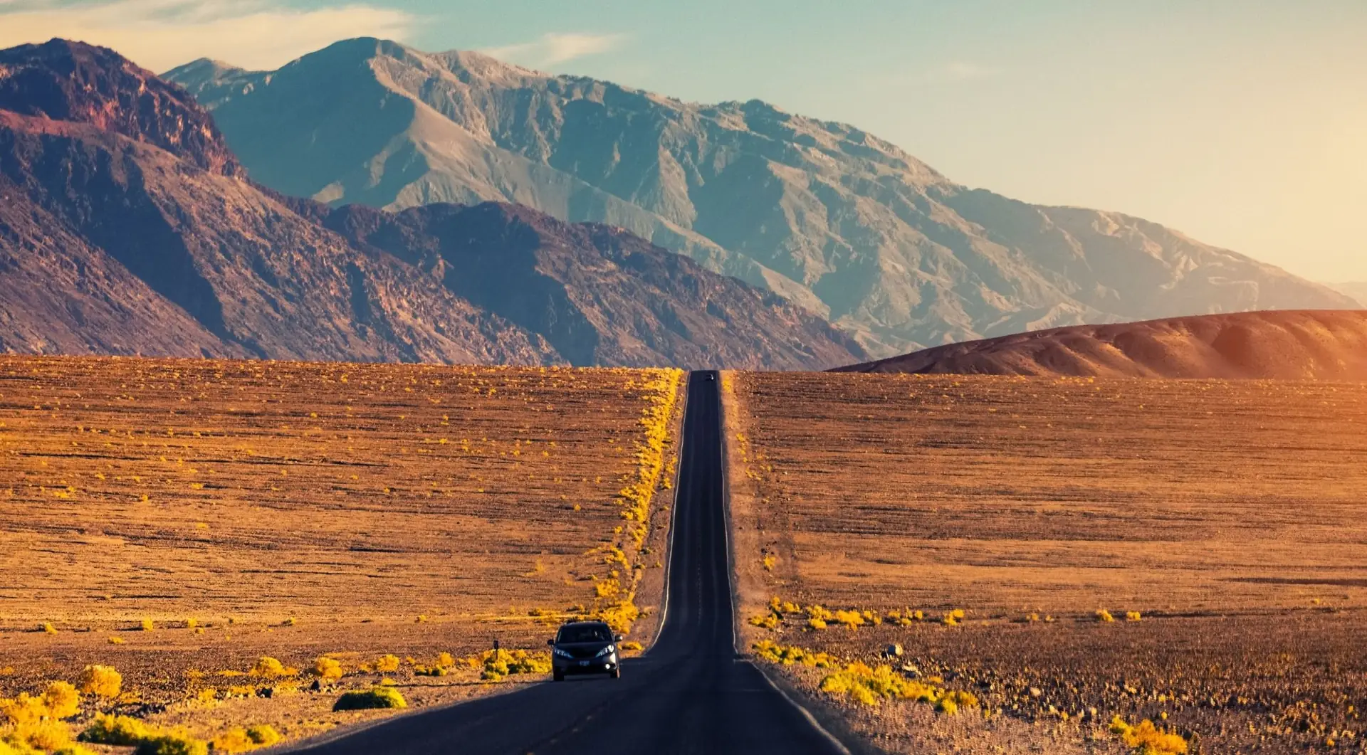 Straight desert road leading toward Death Valley mountains
